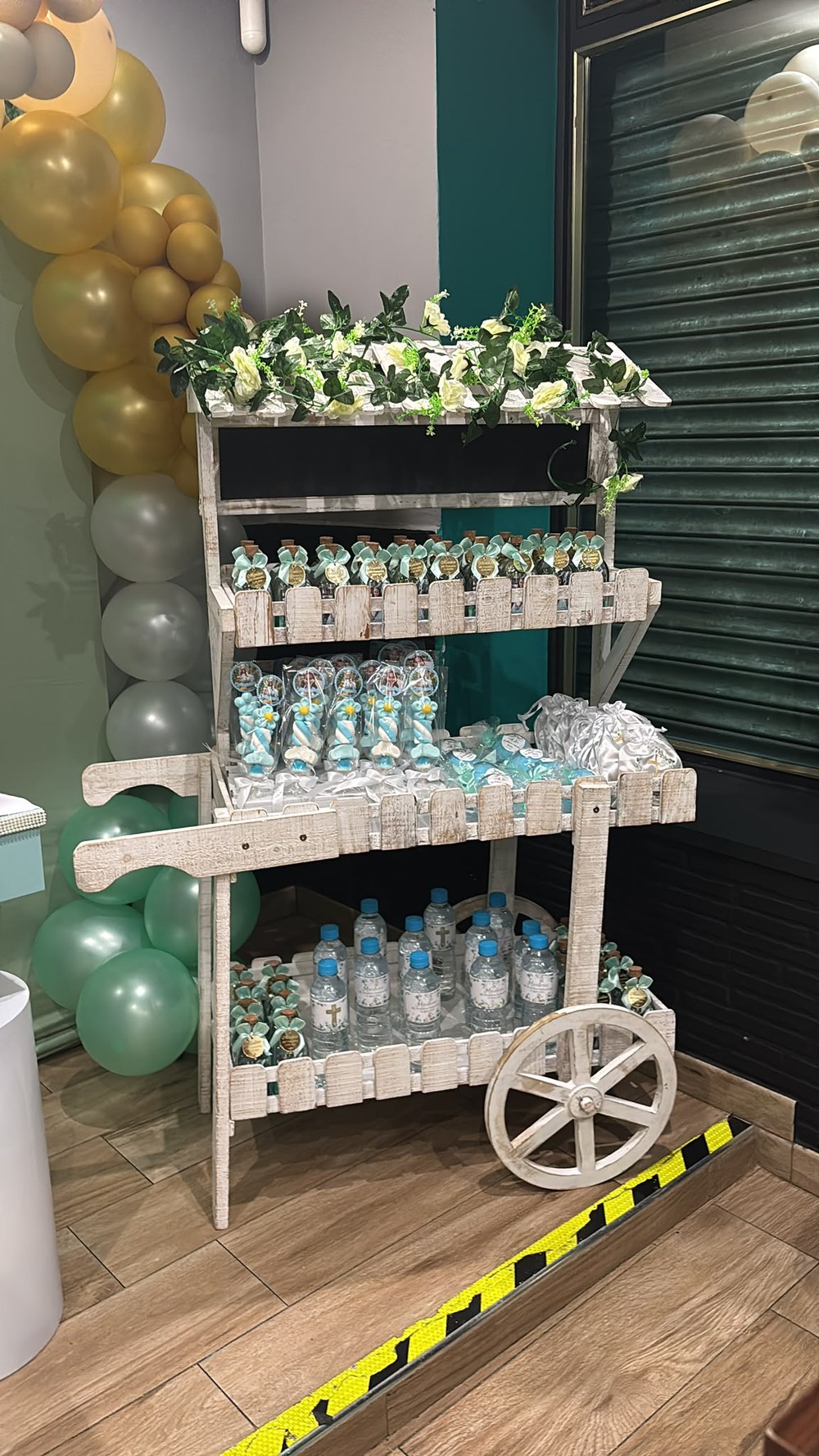 Carrito de madera blanca con flores lleno de recuerdos para invitados