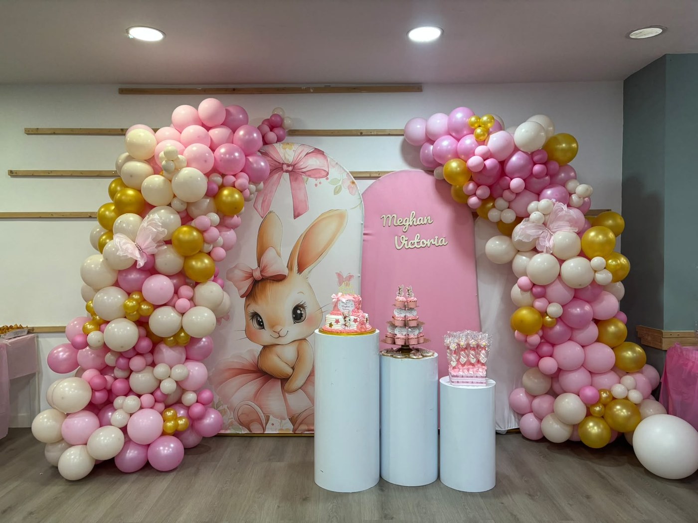Montaje con arco de globos rosa, crema y dorado, panel con conejita y nombre personalizado