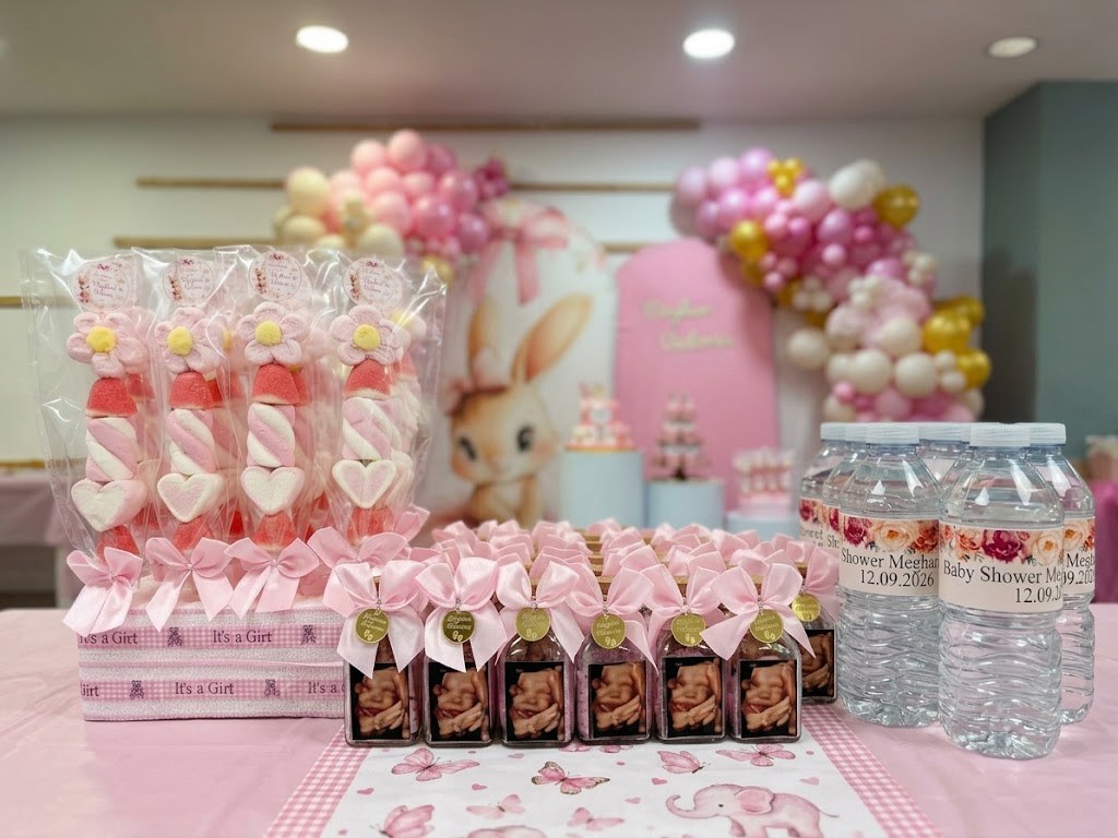 Brochetas de chuches rosas, botellitas con lazo y agua con etiqueta personalizada