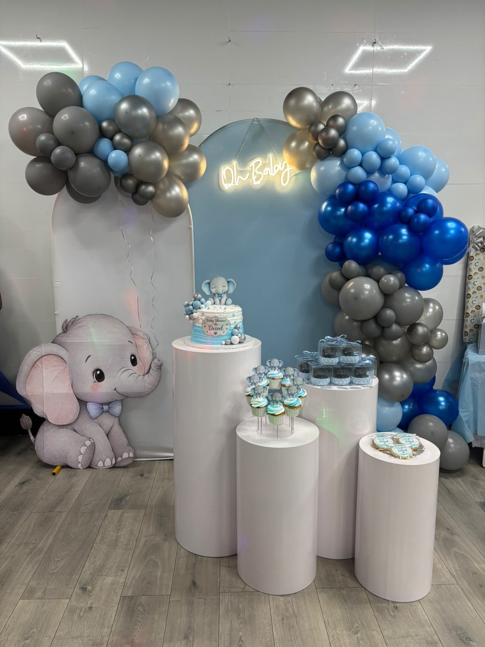 Montaje con arco de globos azul, gris y plata, elefantito y neón Oh Baby