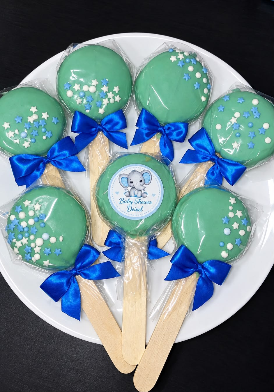 Galletas bañadas en verde con estrellitas, lazo azul y etiqueta de elefantito para baby shower
